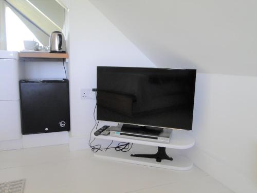 een flatscreen-tv op een stand in een kamer bij Cober House in Helston