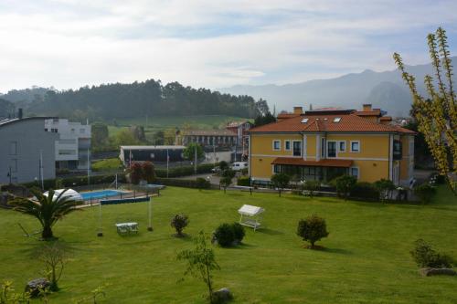a green yard with a yellow house in a city at Hotel Finca La Mansión in Llanes
