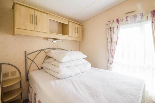1 dormitorio con 1 cama con sábanas blancas y ventana en Great 6 Berth Caravan For Hire At Cherry Tree Holiday Park In Norfolk Ref 70801c en Great Yarmouth