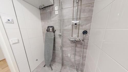 a shower in a bathroom with white tiles at Näsijärvi lakeview apartment in Tampere