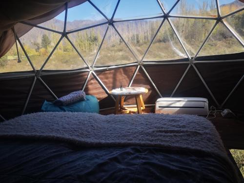 Glamping Mendoza في سيوداد لوجان دي كويو: غرفة نوم في خيمة القبة مع سرير وطاولة