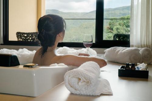 a woman in a bath tub with a glass of wine at Mirante da Colyna Hotel & SPA in Monte Verde