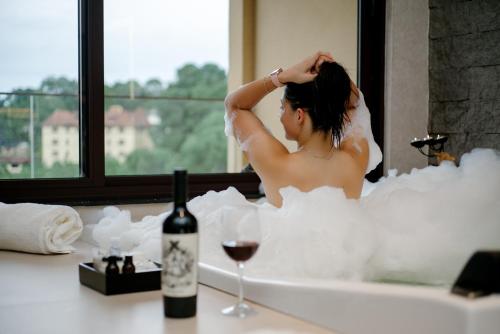 a woman in a bath tub with a glass of wine at Mirante da Colyna Hotel & SPA in Monte Verde