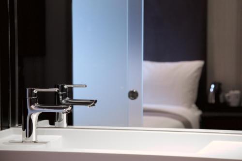 a bathroom sink with a faucet in front of a mirror at The Z Hotel Shoreditch in London