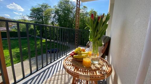 einen Tisch mit Obst und eine Vase Blumen auf dem Balkon in der Unterkunft Apartament Park in Przemyśl