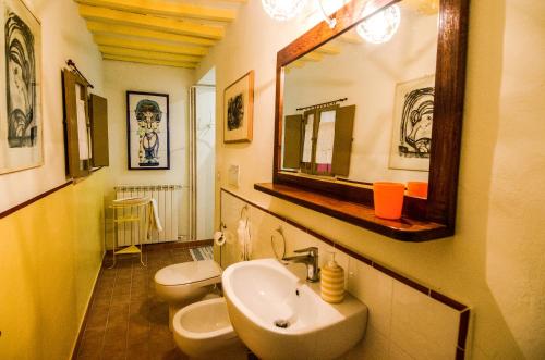 ein Badezimmer mit 2 WCs, einem Waschbecken und einem Spiegel in der Unterkunft Casa vacanze Fatucchi in Foiano della Chiana