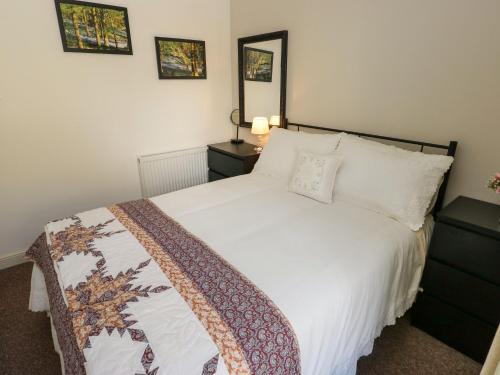 a bedroom with a bed with a white comforter at Canal View Cottage in Keighley