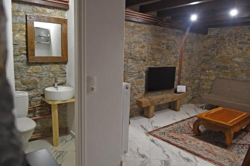 a bathroom with a sink and a toilet and a television at The Stonewall House - at the old town of Samos in Vathý