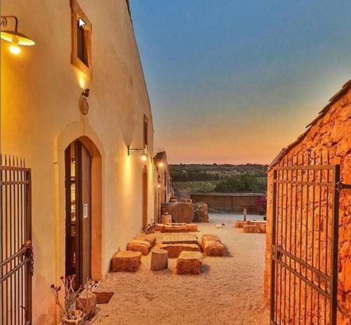 a building with a gate with a sunset in the background at Casette Marianeddi -Agriturismo Marianeddi in Noto