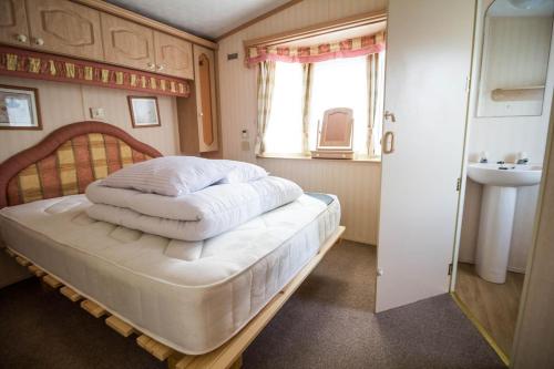 1 dormitorio con cama, ventana y lavamanos en 6 Berth Caravan In Hunstanton, Ideal For Seaside Holidays Ref 13004l, en Hunstanton