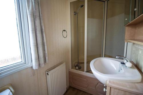 y baño con lavabo y ducha. en 6 Berth Caravan In Hunstanton, Ideal For Seaside Holidays Ref 13004l, en Hunstanton