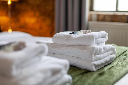 una pila de toallas sentadas encima de una cama en Stunning Loft-Style Duplex 2 BDR Apt in Bow en Londres