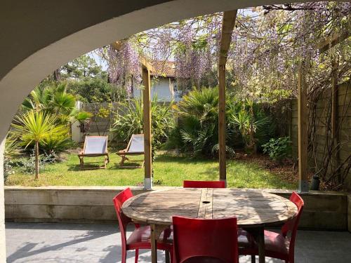 une table et des chaises dans une terrasse avec un jardin dans l'établissement Appartement La Gravière, à Soorts-Hossegor