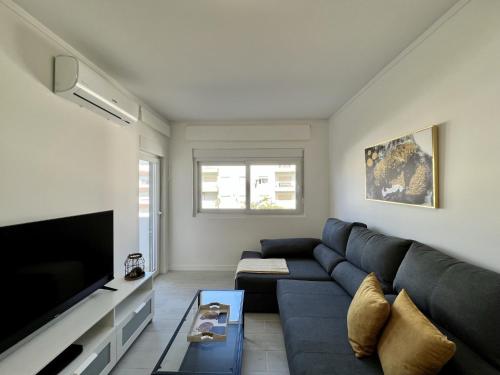 a living room with a blue couch and a flat screen tv at Tavira Central by Homing in Tavira