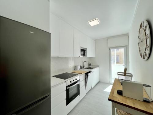 a kitchen with white cabinets and a black refrigerator at Tavira Central by Homing in Tavira