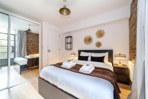 a bedroom with a large bed with two towels at Stunning Loft-Style Duplex 2 BDR Apt in Bow in London