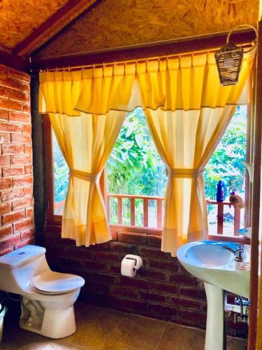 bagno con servizi igienici, lavandino e finestra di Munay Wasi a Baños