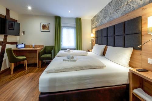 a hotel room with a large bed and a desk at AKZENT Hotel Restaurant Roter Ochse Rhens bei Koblenz in Rhens