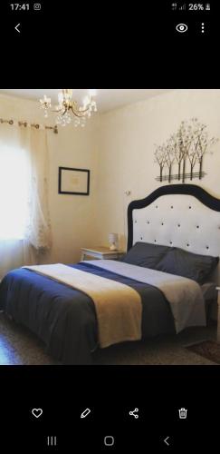 a bedroom with a large bed and a chandelier at La cascina della grotta di tufo in San Valentino