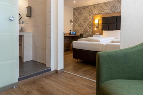 a hotel room with a bed and a bathroom at AKZENT Hotel Restaurant Roter Ochse Rhens bei Koblenz in Rhens