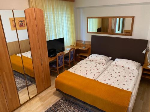 a small bedroom with a bed and a television at Pension Carinthia in Unterburg am Klopeiner See