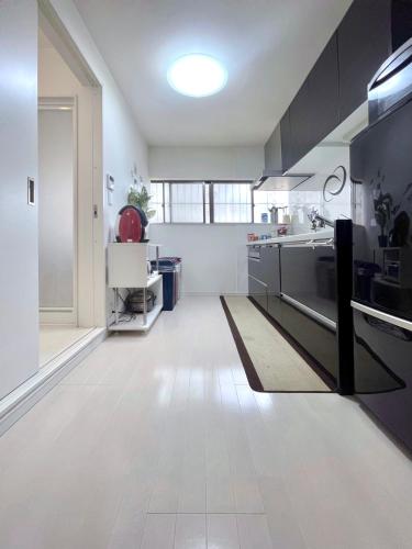 a kitchen with white floors and black cabinets at guesthouse中道 in Osaka