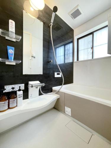 a bathroom with a bath tub and a sink at guesthouse中道 in Osaka
