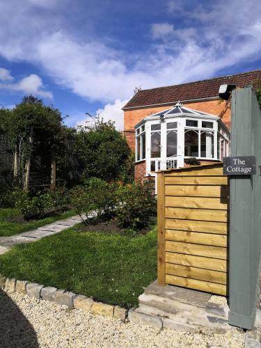 una casa con una puerta de madera frente a un edificio en Rose Cottage Glastonbury en Glastonbury