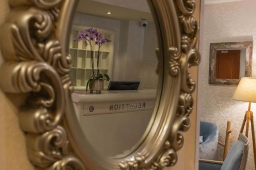 a mirror with a vase of flowers in a room at Mali Hotel Porat in Budva