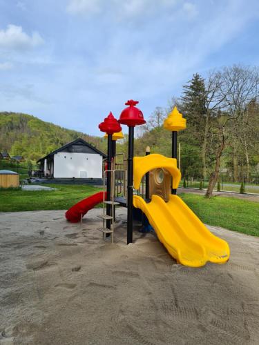 a playground with a yellow slide in a park at DOMKI POD ZIELONYM WZGÓRZEM 2 in Kudowa-Zdrój