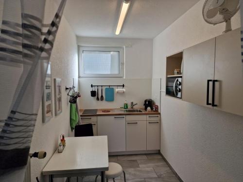 eine kleine weiße Küche mit einem Tisch und einem Fenster in der Unterkunft Apartment Ferreira in Iseltwald