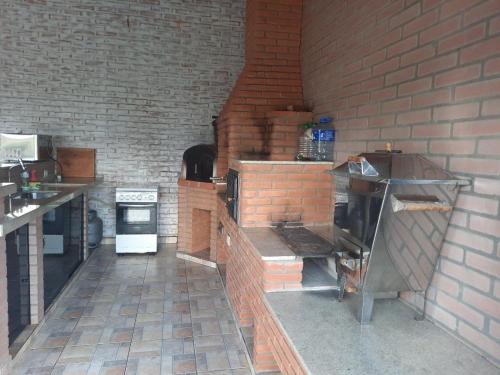 a kitchen with a brick wall and a brick oven at Chácara Recanto Feliz in Ibiúna