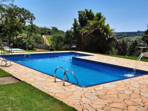 una piscina en un patio con un patio de piedra en Chácara Recanto Feliz, en Ibiúna