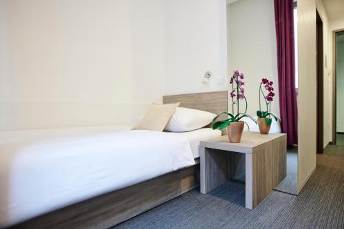 a bedroom with a bed and a table with potted plants at Hotel Meksiko in Ljubljana