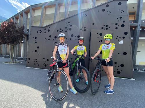 three people standing next to their bikes in front of a climbing wall at Residence & Sportlodges Claudia in Plaus