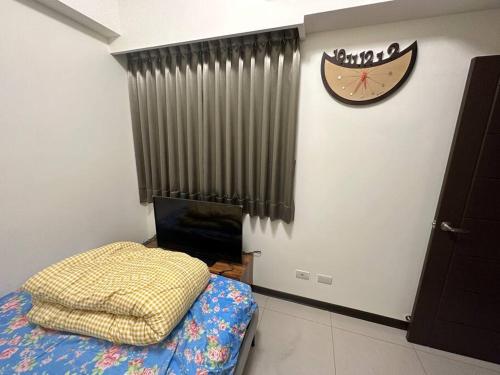 a bedroom with a bed and a clock on the wall at MingHOW'S House 清水海線溫馨客房有雙人床位、電視、冷氣、獨立衣櫃 in Erh-t'ang-lang