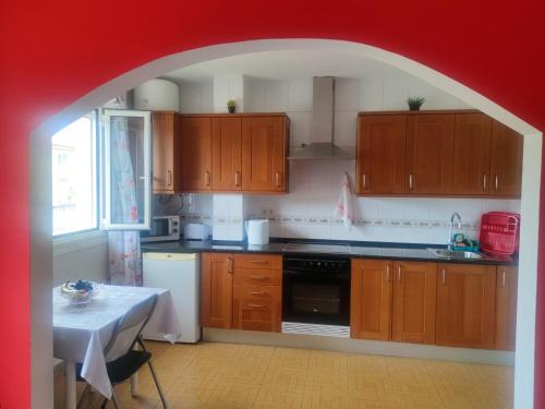 una cocina con armarios de madera y un arco rojo en Apartamentos turísticos Lemos en Pedrouzo