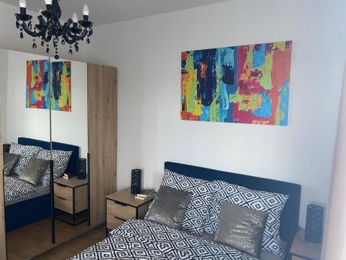 烏涅尤夫的住宿－UniLove Apartamenty，客厅配有一张床,墙上挂有绘画作品