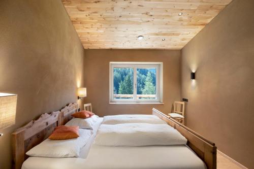 two beds in a room with a window at Pitschlhof Apt Zirbe in Aldino