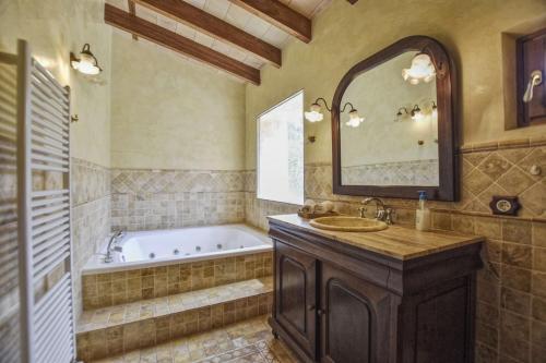 ein Badezimmer mit einer Badewanne, einem Waschbecken und einem Spiegel in der Unterkunft Can Petit in Sant Joan