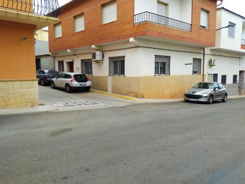 zwei Autos auf einem Parkplatz neben einem Gebäude geparkt in der Unterkunft Cal surdo in Bolbaite