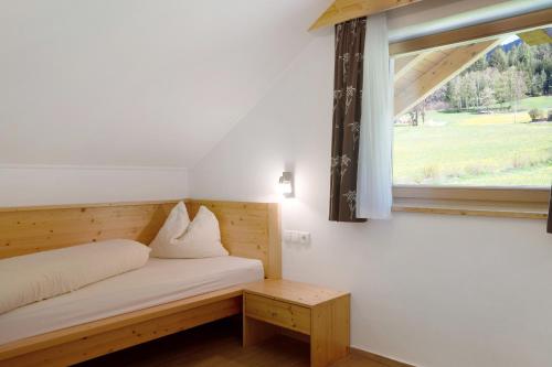 um pequeno quarto com uma cama e uma janela em Stiflerhof Apt Alpenrose em Falzes