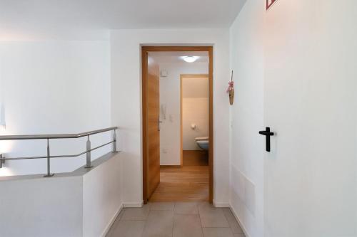 a hallway with a cross on the wall and a bathroom at Stiflerhof Apt Alpenrose in Falzes