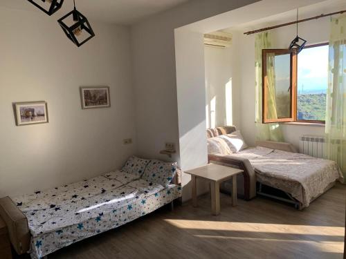 1 dormitorio con 2 camas, mesa y ventana en NiCE ViEW en Ereván