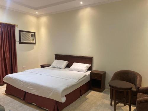 a bedroom with a large bed and a chair at دارك2 in Yanbu
