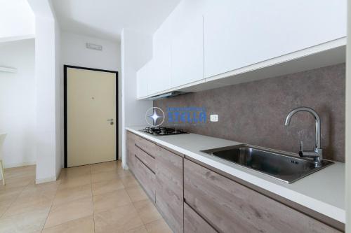 uma cozinha com armários brancos e um lavatório em Condominio Stella em Lido di Jesolo