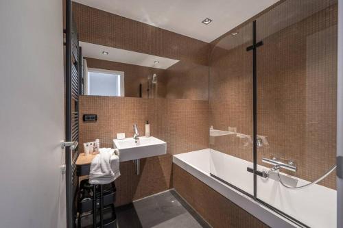 BEACH 52 duplex appartement met terras في كنوك هايست: حمام مع حوض وحوض استحمام