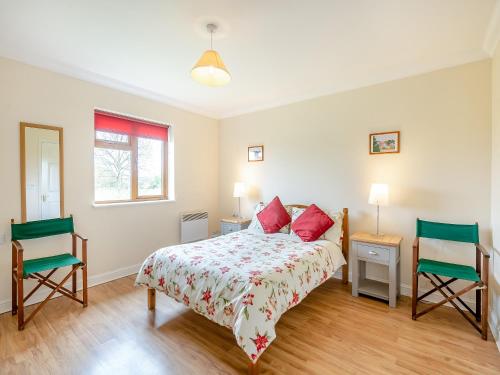 a bedroom with a bed and two chairs at Dairy Cottage in Saint Osyth