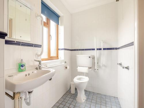 La salle de bains blanche est pourvue d'un lavabo et de toilettes. dans l'établissement Dairy Cottage, à Saint Osyth