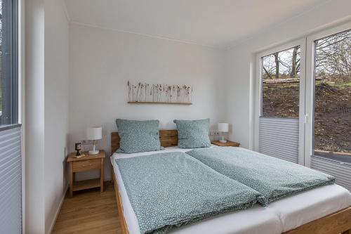 a white bedroom with a bed and two windows at Tinyhaus Brekendorf Kammberg in Brekendorf